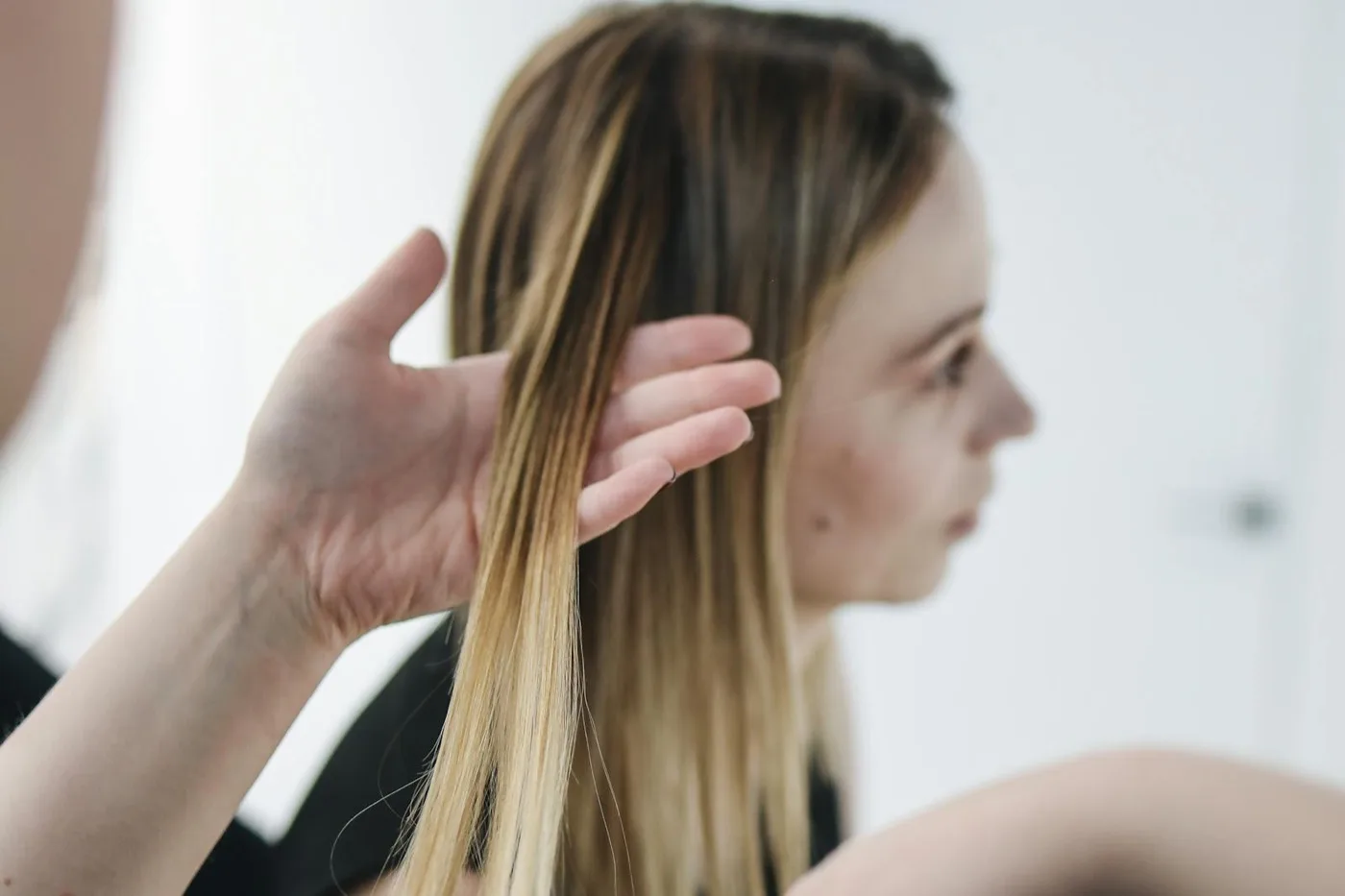 Main vérifiant un balayage blond sur cheveux longs